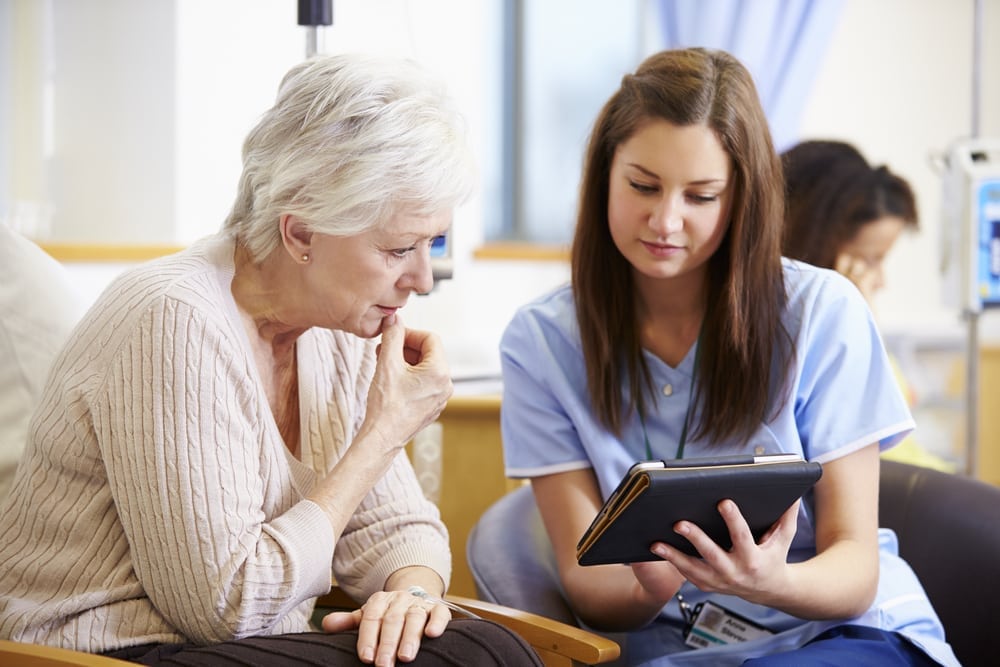 older woman looking at ipad with nurse