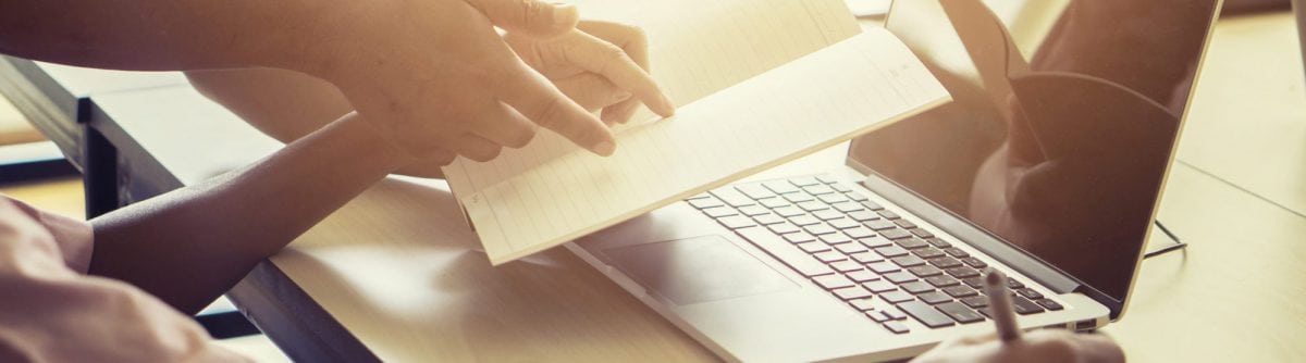 guy on laptop writing notes