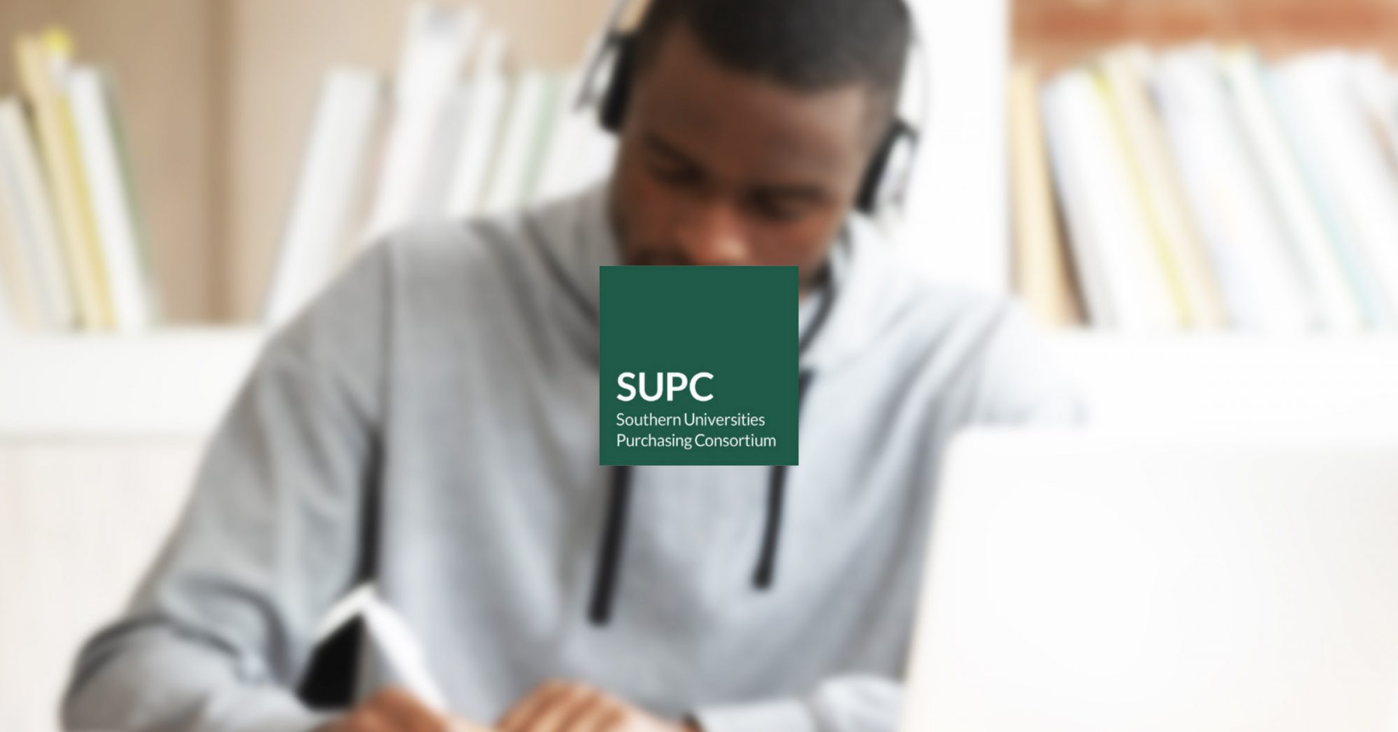 student writing behind a desk with SUPC logo in the middle