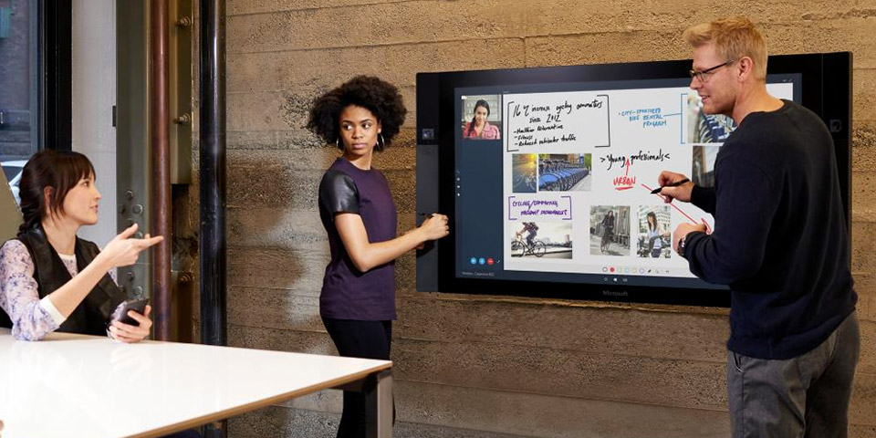 two people presenting in a room on a large screen